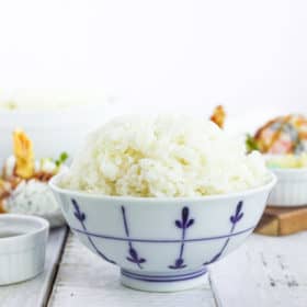 a white bowl with sushi rice on a white board