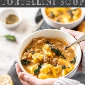 A hand holding a white bowl of Instant Pot Tortellini Soup