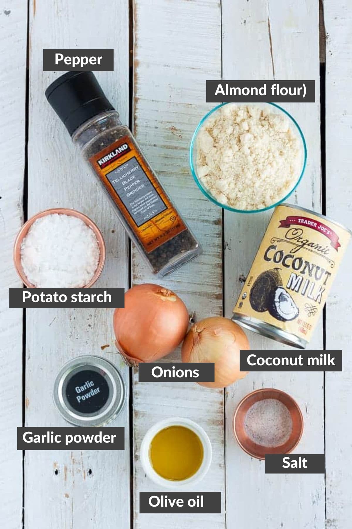 Onions, coconut milk, olive oil, and other ingredients on a white wooden board.