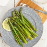 frozen asparagus on a grey plate with a lemon slice