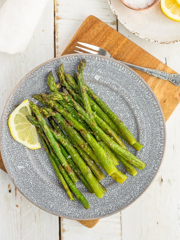 frozen asparagus on a grey plate with a lemon slice