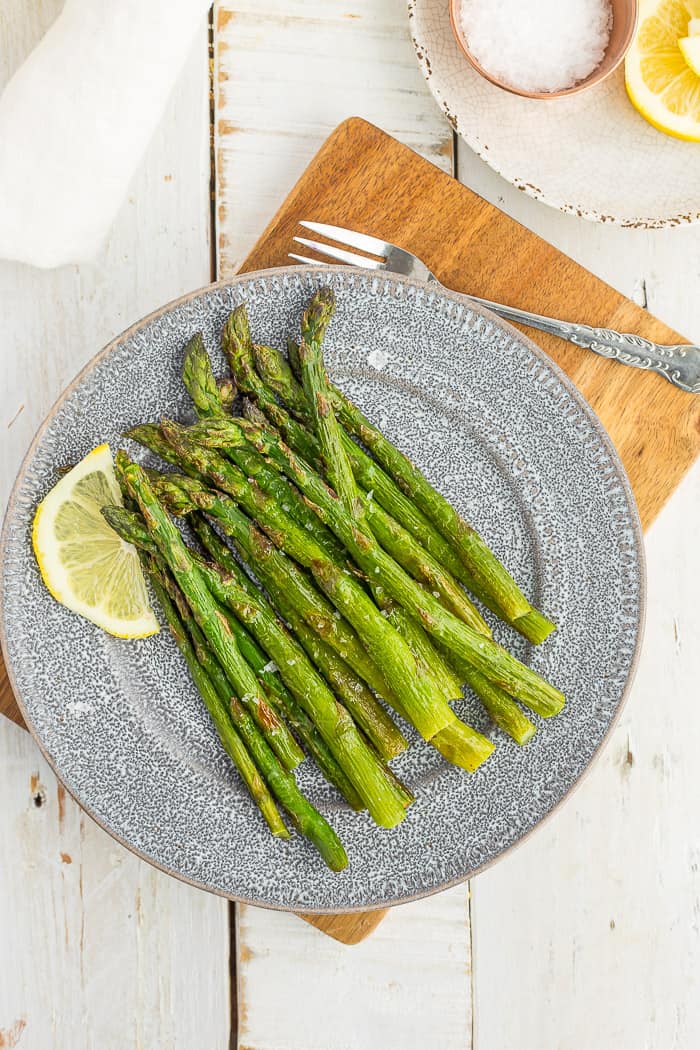 frozen asparagus on a grey plate with a lemon slice