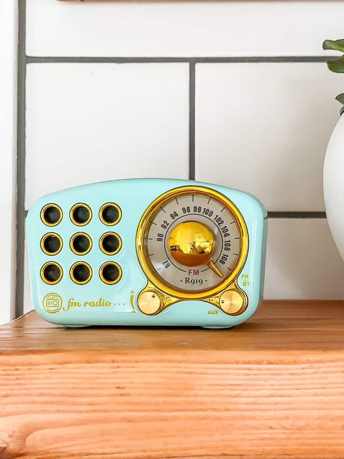 a small teal bluetooth radio on a wooden shelf