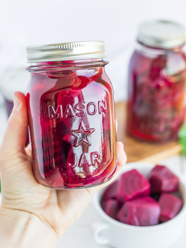 a hand holding a canning jar of beets