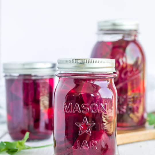 3 canning jars with beets and parsley on a white board