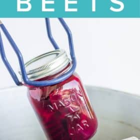 tongs holding a canning jar of beets