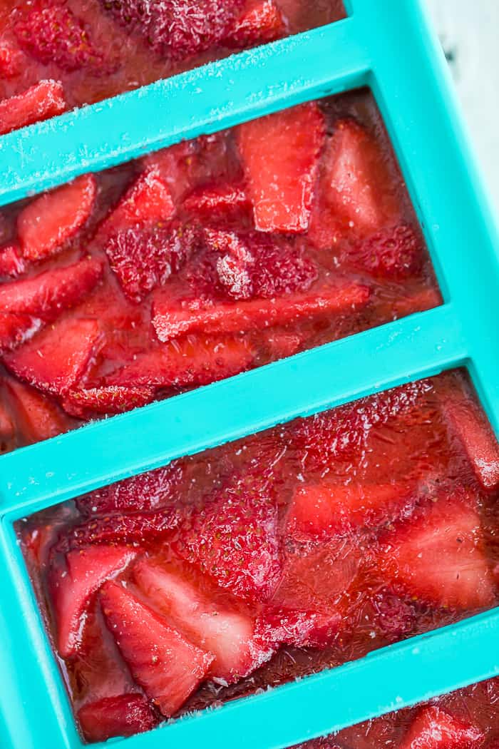 a blue freezer tray with frozen strawberry syrup