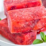 bricks of frozen strawberries in syrup on a white plate with a sprig of mint