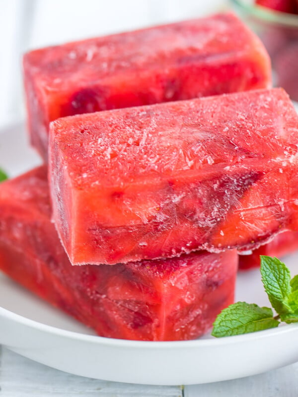 bricks of frozen strawberries in syrup on a white plate with a sprig of mint