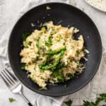 a black bowl with asparagus ravioli and a fork