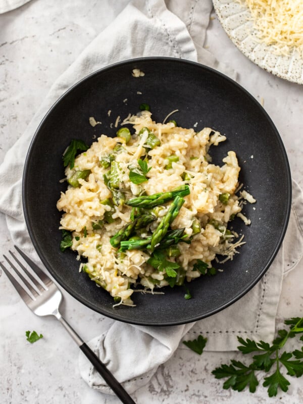 a black bowl with asparagus ravioli and a fork