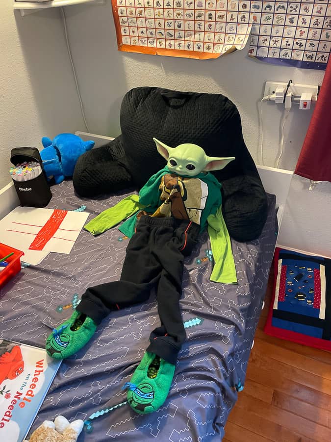 a baby yoda on a bed wearing clothes