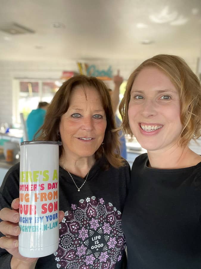 2 women smiling, one holding a cup