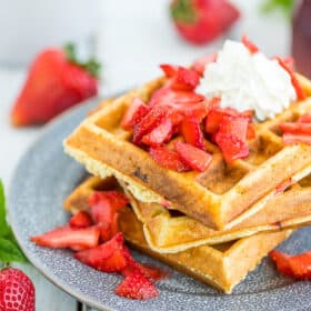Strawberry waffles topped with sliced strawberries and whipped cream