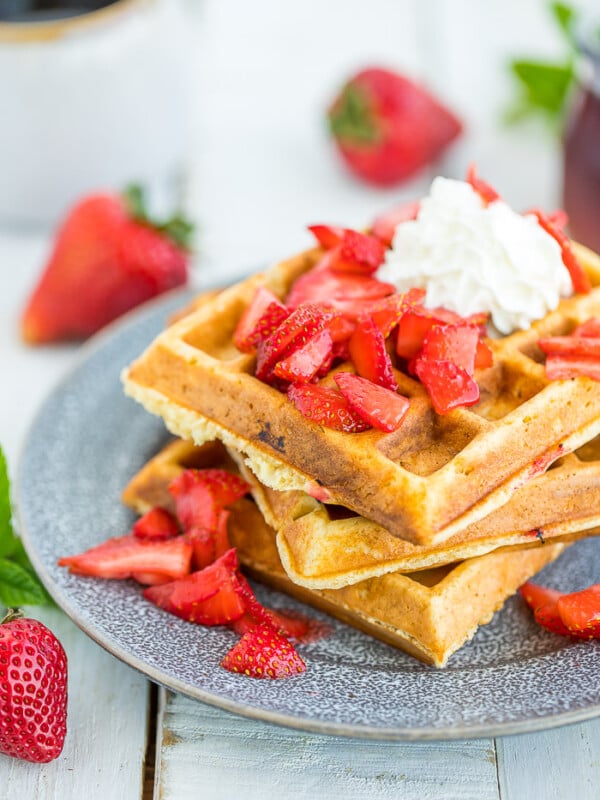 Strawberry waffles topped with sliced strawberries and whipped cream