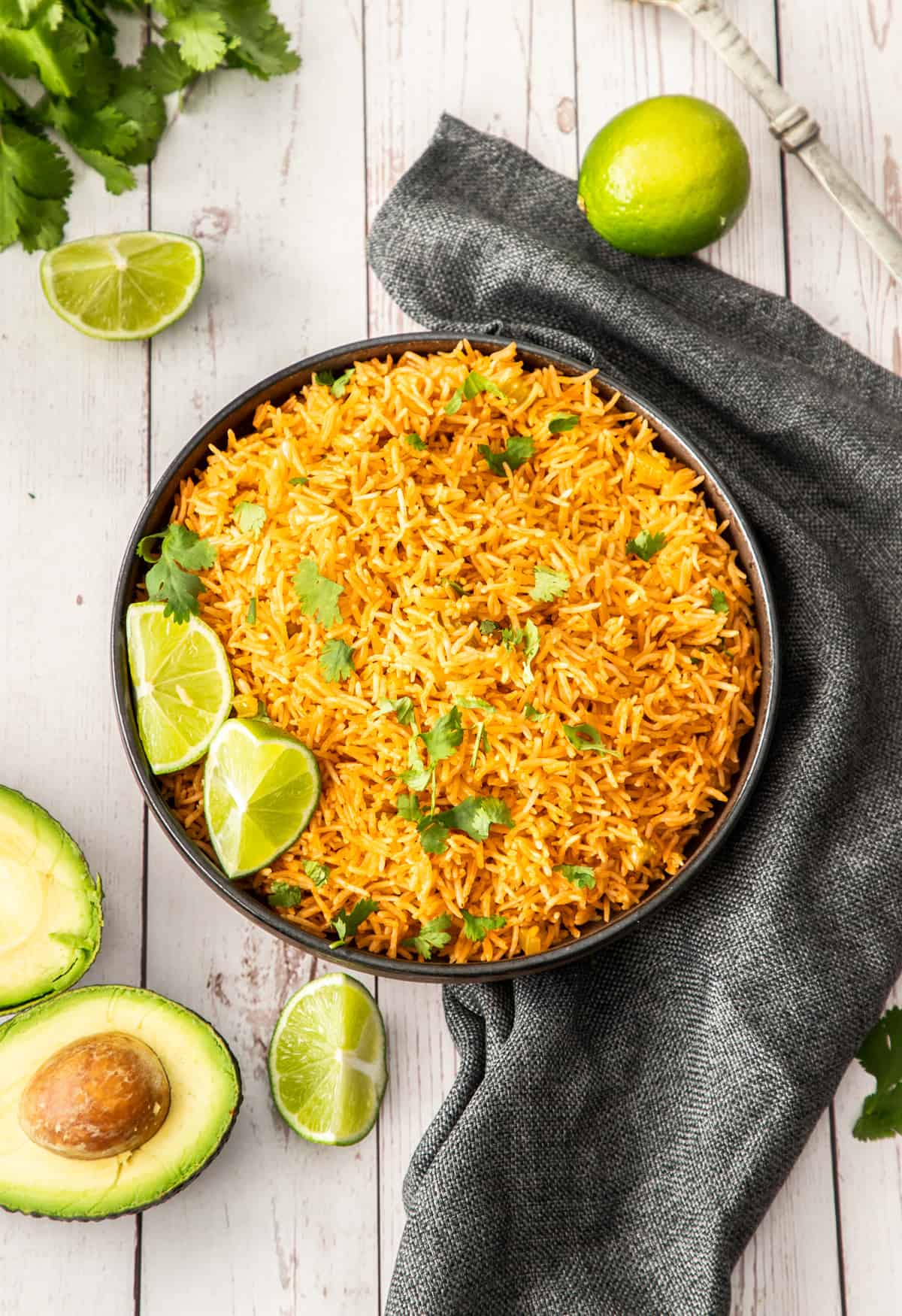 a black bowl of Instant Pot Mexican rice topped with cilantro and lime wedges.