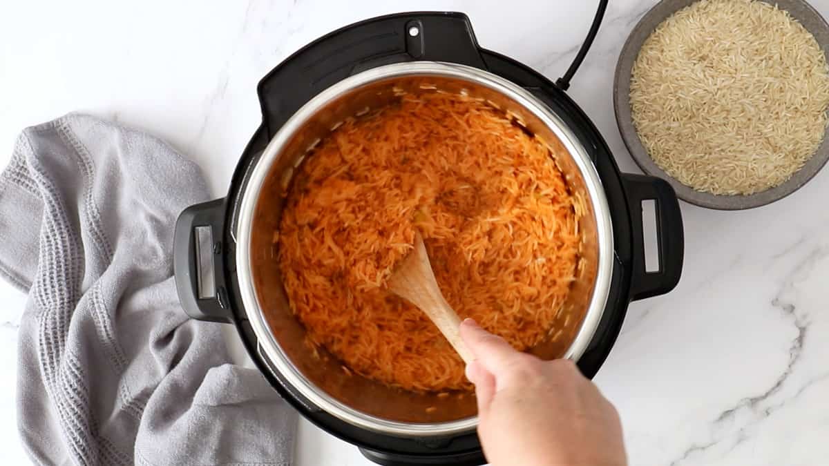 A wooden spoon stirring Mexican rice in an Instant Pot.