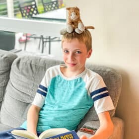 a boy with a stuffed cat on his head