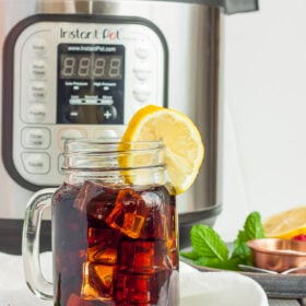 a canning jar full of Instant Pot iced team with a slice of lemon in front of an Instant Pot.
