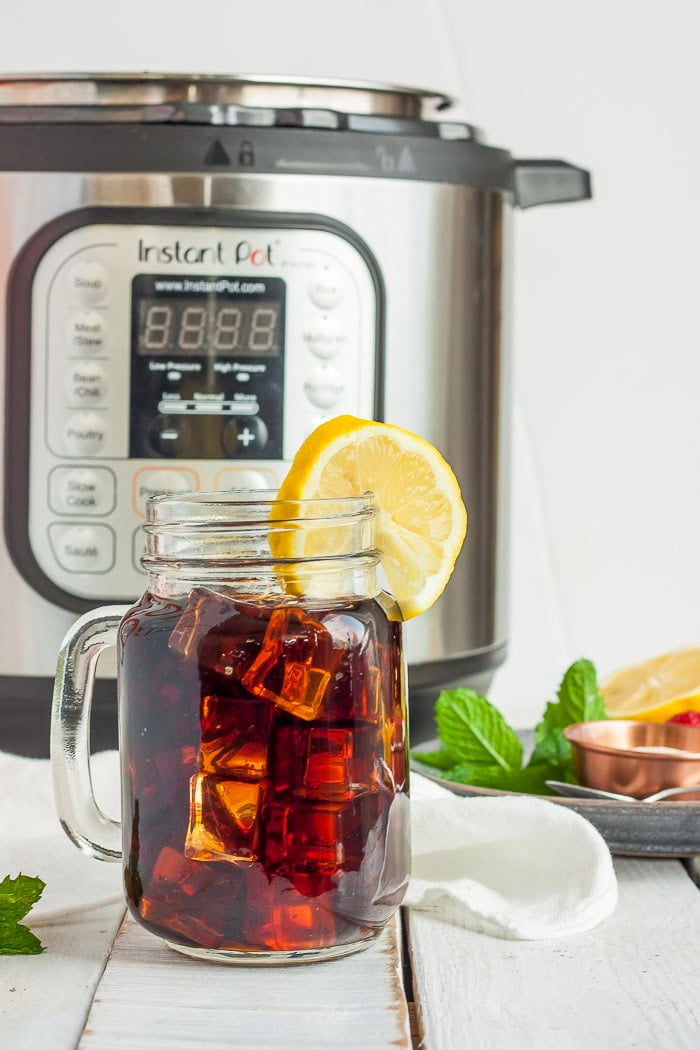 a canning jar full of Instant Pot iced team with a slice of lemon in front of an Instant Pot.