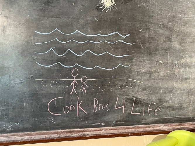 a chalkboard with stick figure drawings that says "cook bros for life"