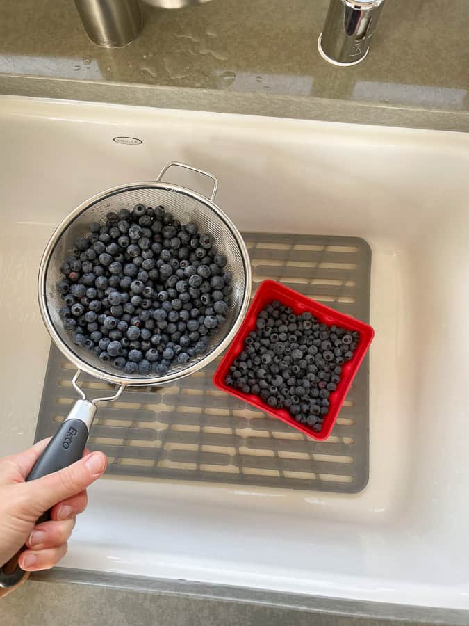 2 baskets of blueberries in a sink