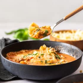 a spoon lifting a bite of Instant Pot Lasagna Soup over a dark grey bowl
