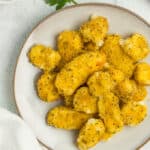 a grey plate with air fryer cheese curds, parsley, and a bowl of dipping sauce