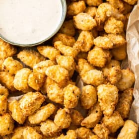 air fryer popcorn chicken on a baking sheet with a bowl of dipping sauce