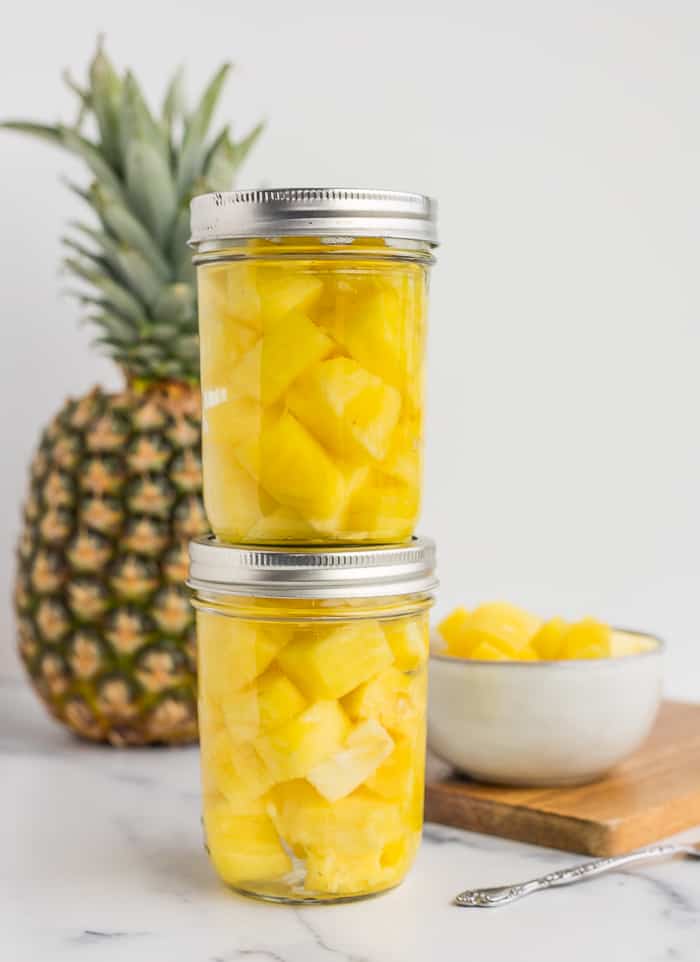 two jars of preserved pineapple stacked on top of each other