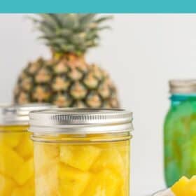 3 pint jars of canned pineapple on a white board with a full pineapple and a bowl of pineapple