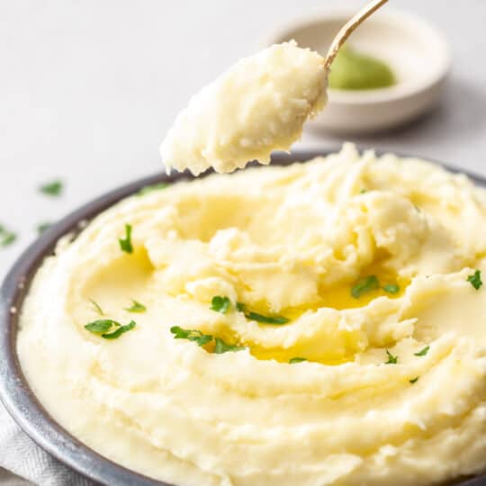 a spoonful of mashed potatoes over a bowl