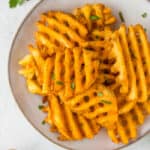 a grey dish with air fried waffle fries and a dish of ketchup