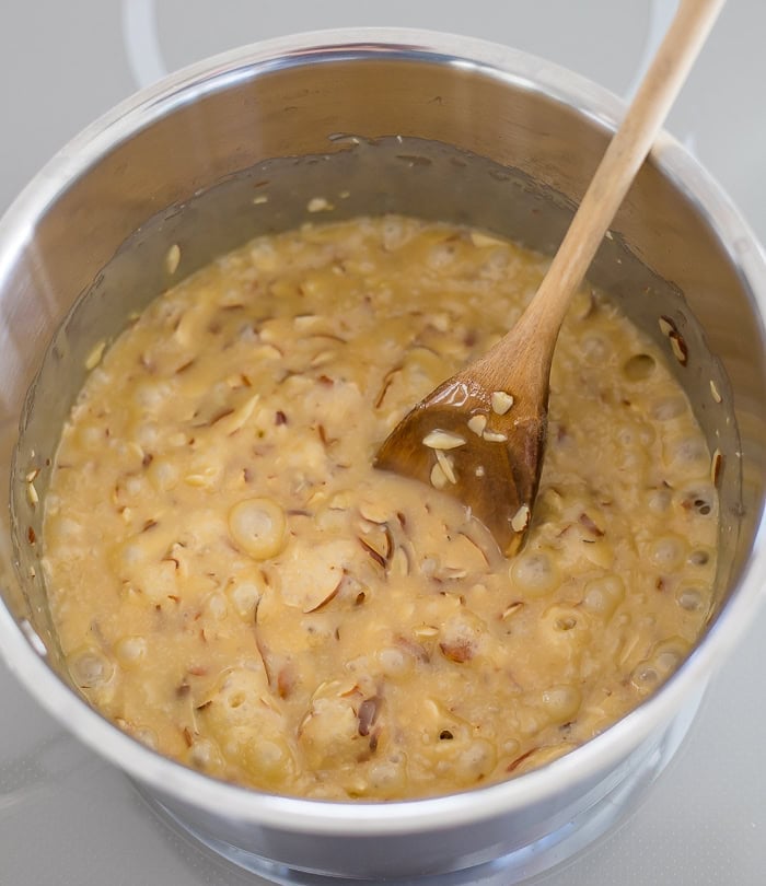 a saucepan with toffee buttercrunch and a wooden spoon.