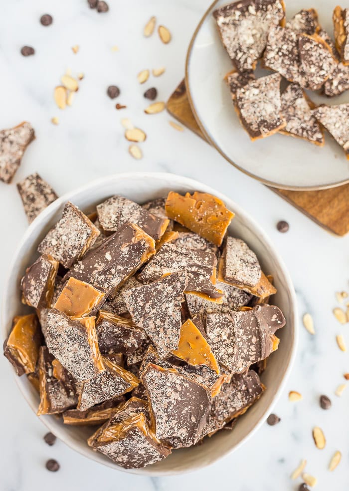 a white bowl of almond roca pieces.