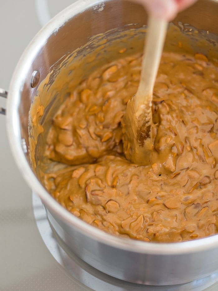 a saucepan with fully-cooked toffee buttercrunch and a wooden spoon.