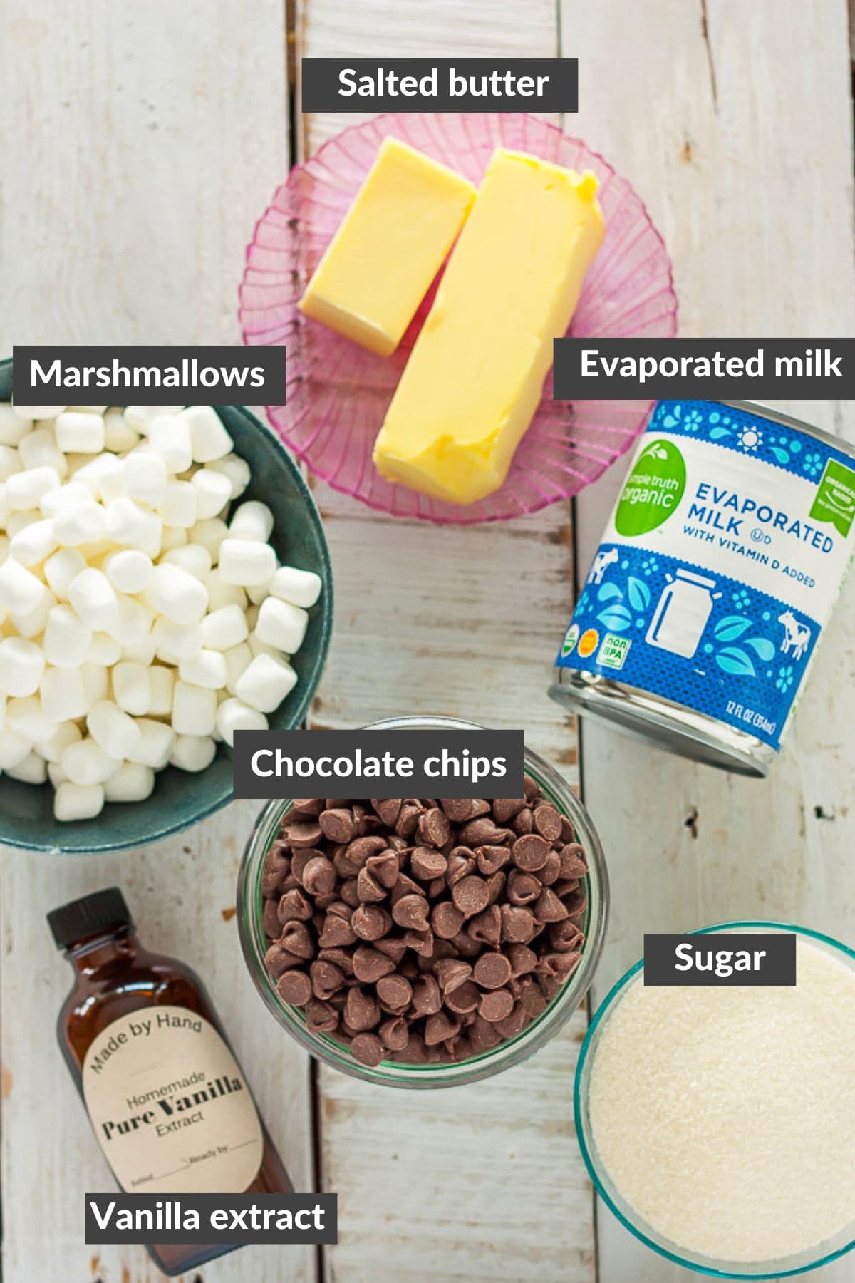 butter, chocolate chips, marshmallows, evaporated milk, sugar, and vanilla extract on white boards.