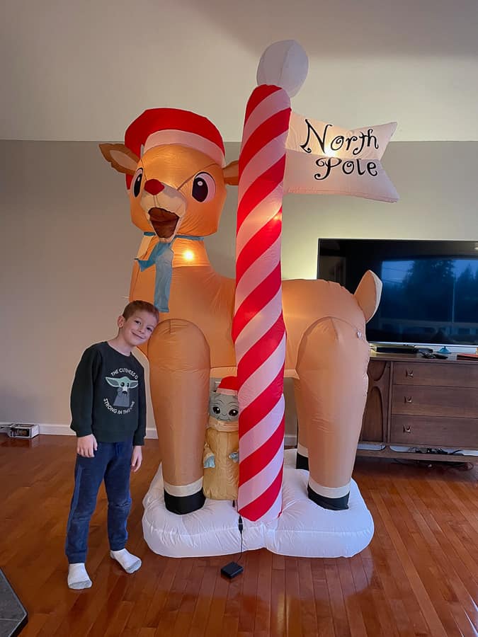 a boy standing next to a christmas inflatable 