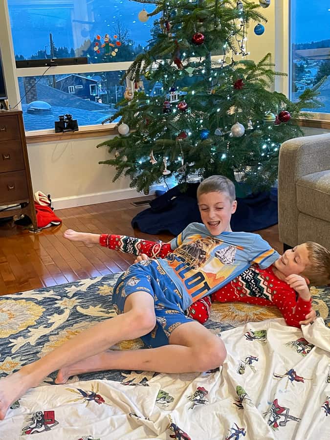 2 brothers wrestling in front of a Christmas tree