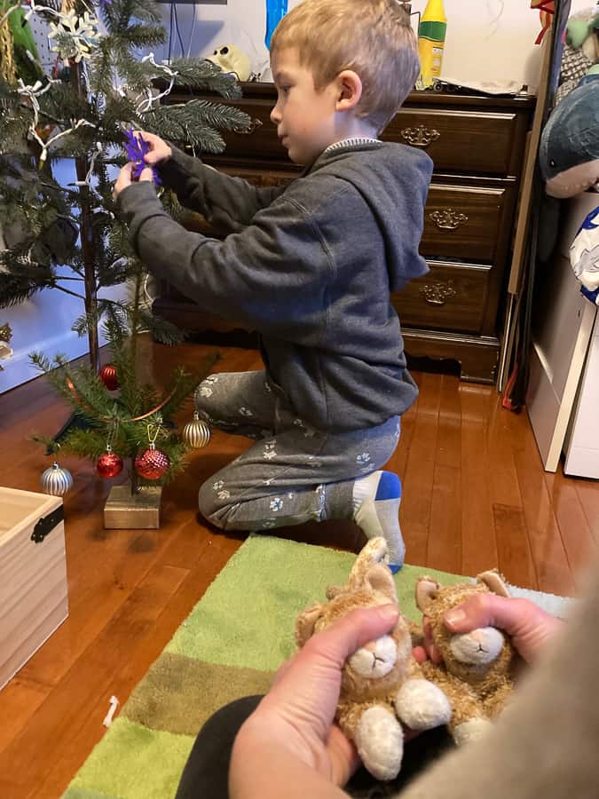 a boy decorating a small christmas tree
