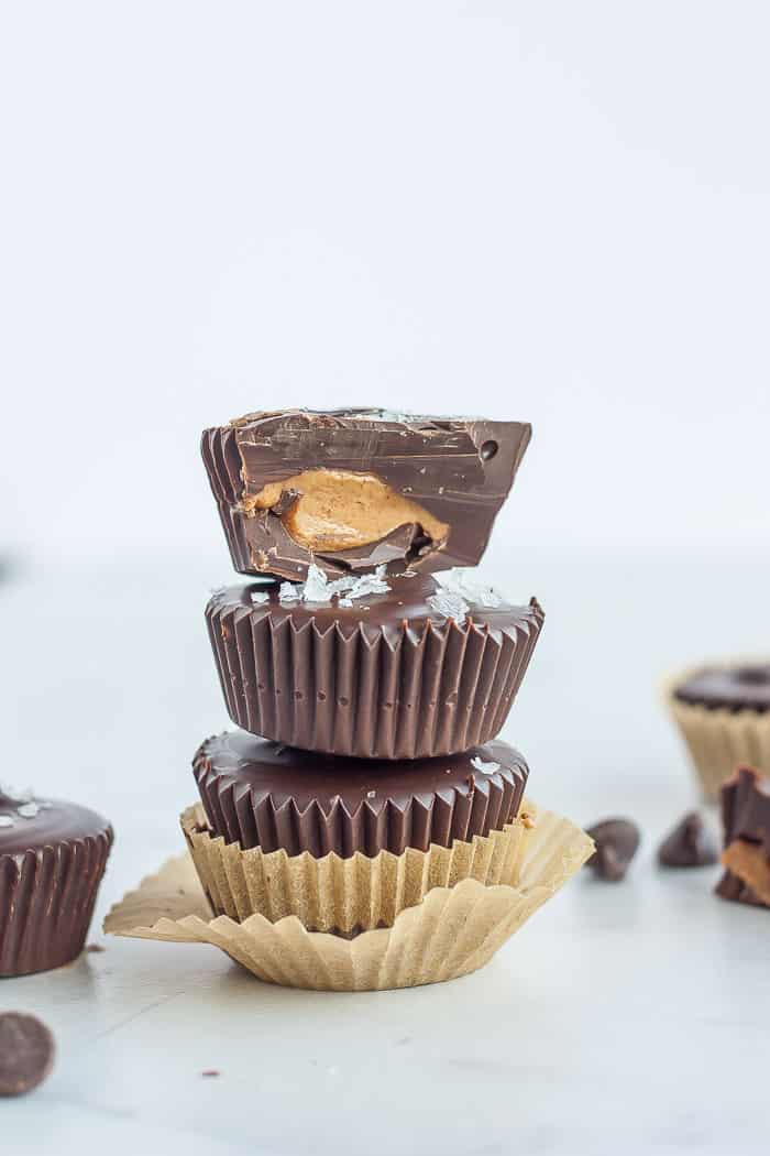 3 dark chocolate almond butter cups stacked on top of each other. Top one is cut in half
