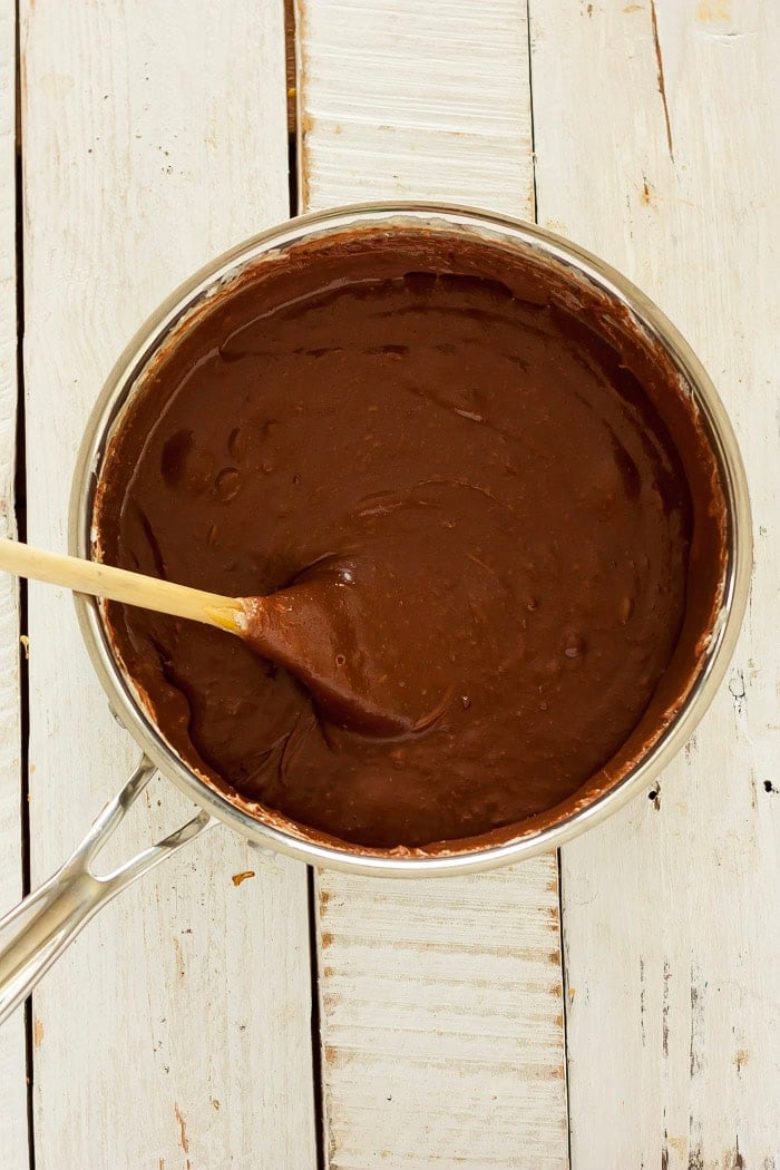 a wooden spoon in a saucepan of liquid chocolate.