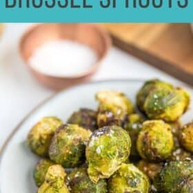 a plate of roasted baby brussel sprouts with a fork on a white board