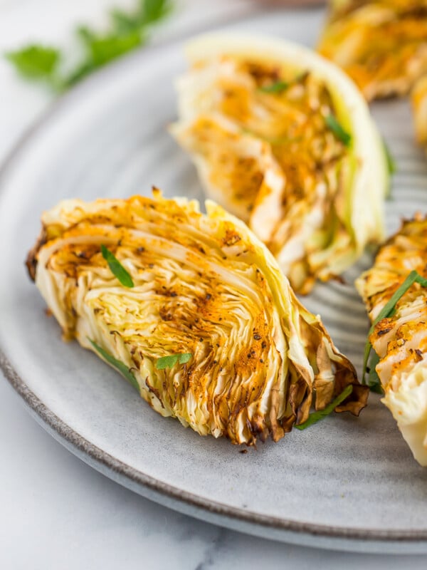 sections of air fryer cabbage on a grey plate topped with parsley