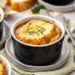 a small black ramekin with instant pot french onion soup topped with bread and melty cheese