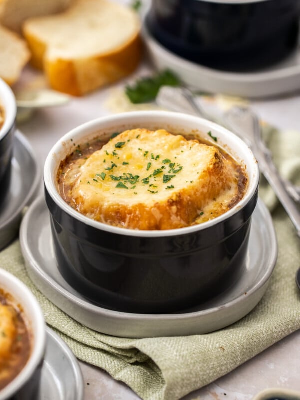 a small black ramekin with instant pot french onion soup topped with bread and melty cheese