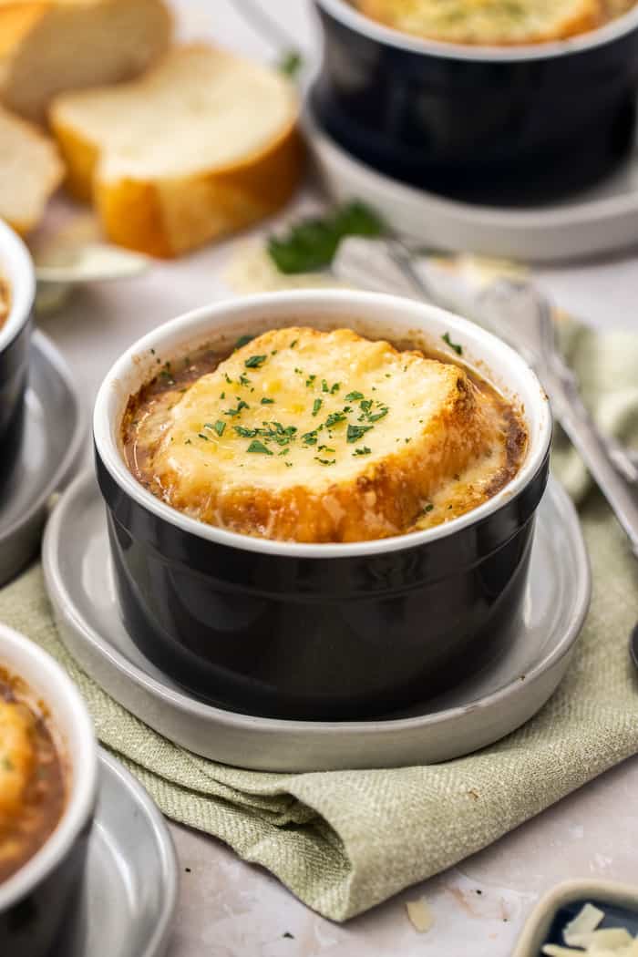 a small black ramekin with instant pot french onion soup topped with bread and melty cheese