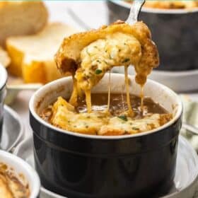 a spoon lifting a bite of french onion soup with bread and cheese