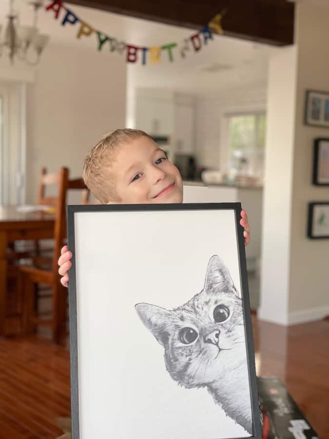 a kid holding a picture of a kitten