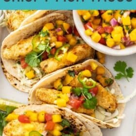 crispy air fryer fish tacos in tortillas on a tray with a bowl of mango salsa